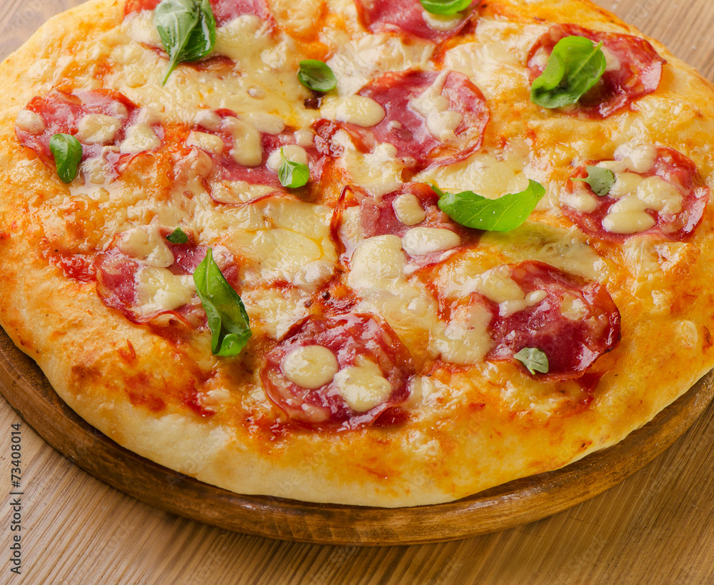 Salami pizza with cheese and basil on board. Salami pizza with cheese and basil on board.