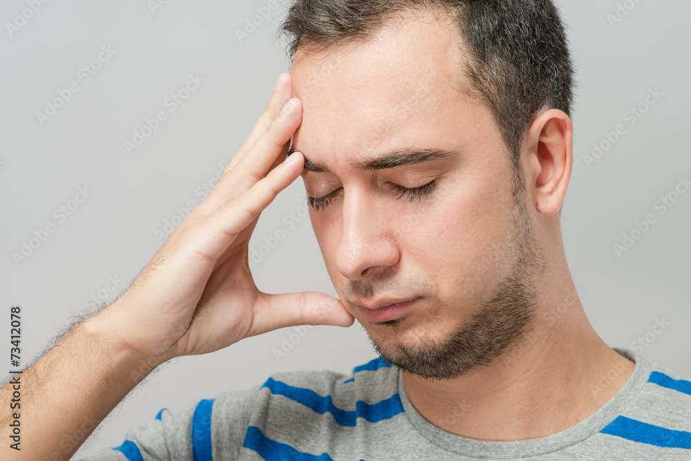 Depressed young man holding head in hands Depressed young man holding head in hands