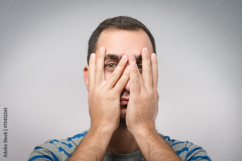 Young Caucasian man hiding his face with hand Young Caucasian man hiding his face with hand