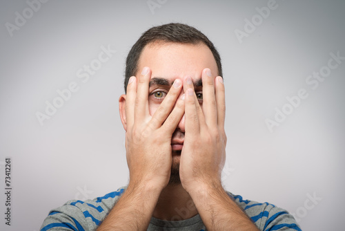 Young Caucasian man hiding his face with hand