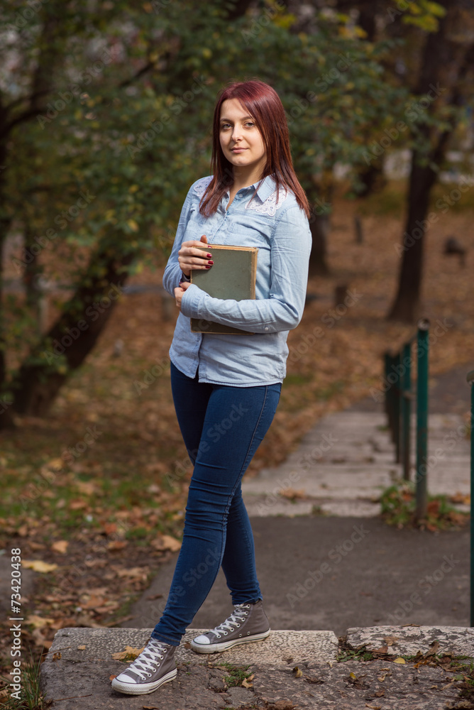 Redhead student girl posing on stairs with a book Redhead student girl posing on stairs with a book