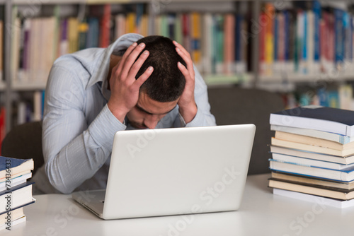 Confused Male Student Reading Many Books For Exam