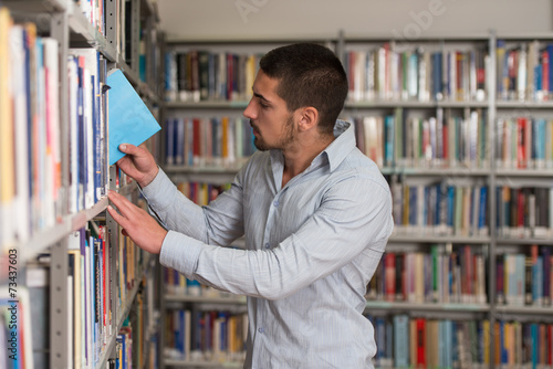 Happy Male Student With Book In Library