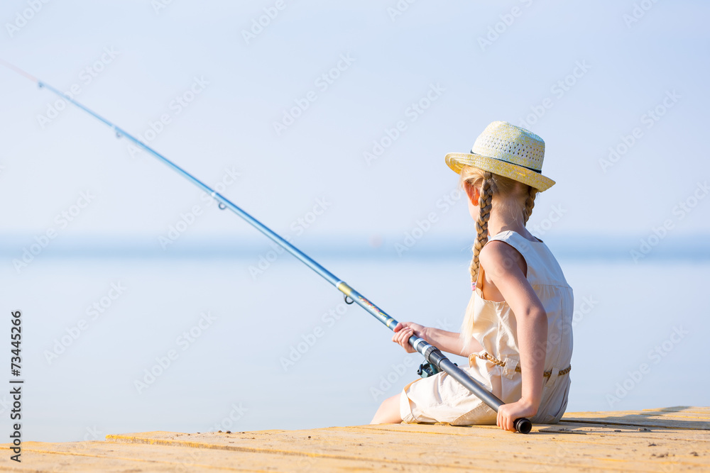 Girl in a dress and a hat with a fishing rod Girl in a dress and a hat with a fishing rod