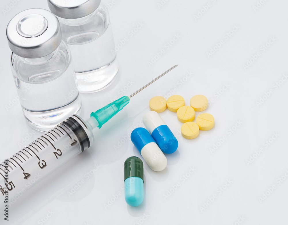 Syringe with medical ampoule and tablets on white background Syringe with medical ampoule and tablets on white background