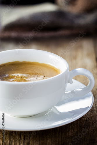 Composition with white cup of coffee on wooden table