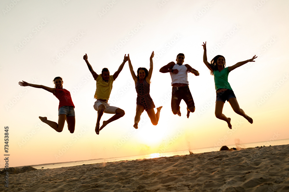 Fototapeta premium smiling friends dancing and jumping on beach
