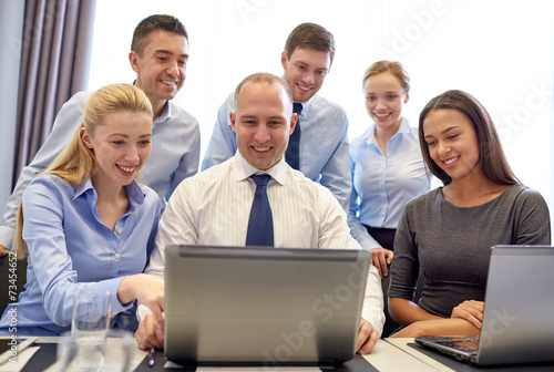 smiling business people with laptop in office