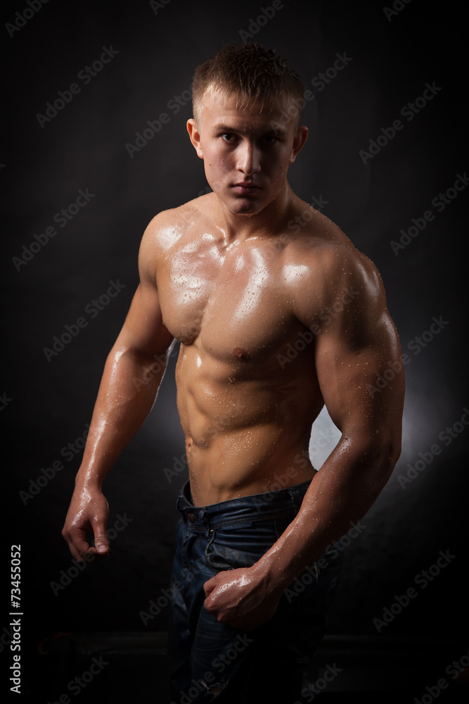 Fototapeta premium Muscular man covered with water drops