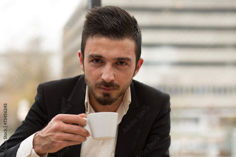 Junger Geschäftsmann trinkt Kaffee, Blick zur Kamera Junger Geschäftsmann trinkt Kaffee, Blick zur Kamera