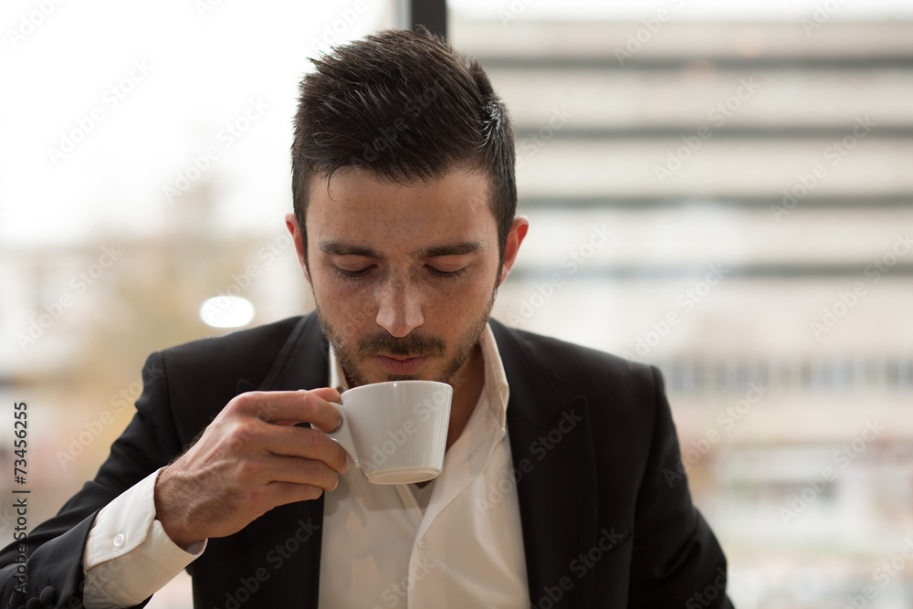 Junger Geschäftsmann trinkt aus Kaffeetasse in Büro Junger Geschäftsmann trinkt aus Kaffeetasse in Büro