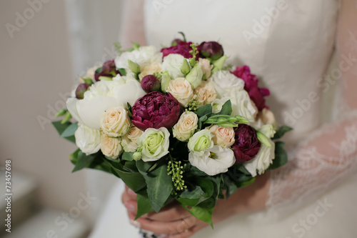 violet and white wedding bouquet of roses in the hands of the br