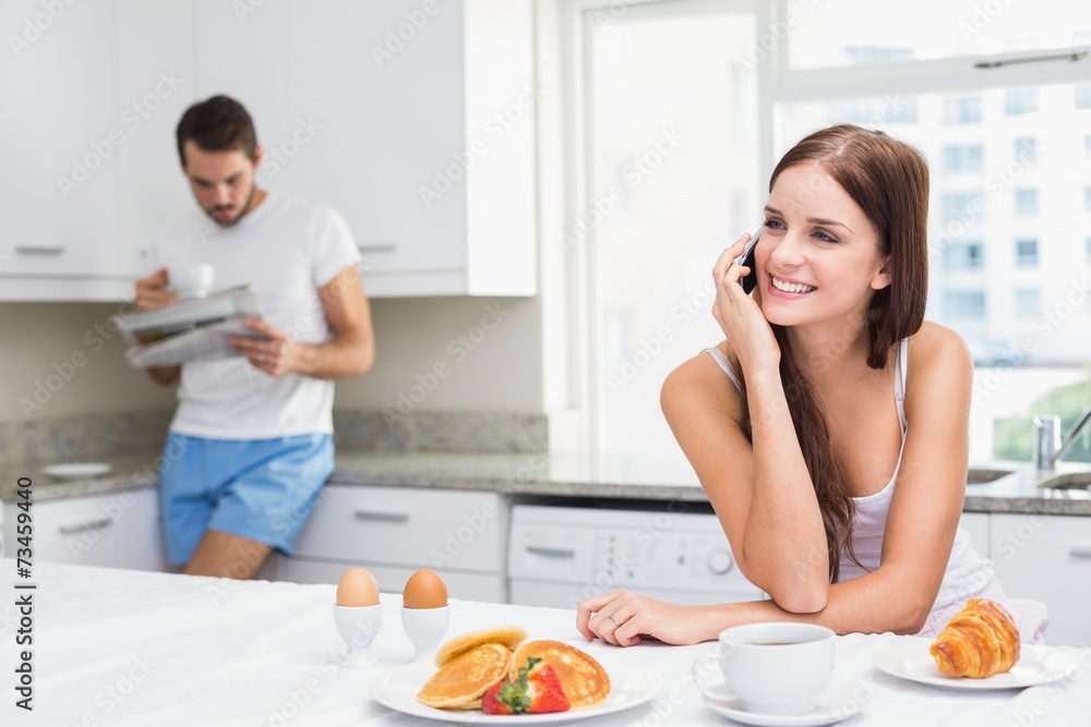 Young woman talking on phone at breakfast