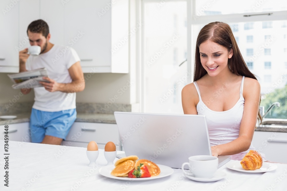 Young woman using laptop at breakfast
