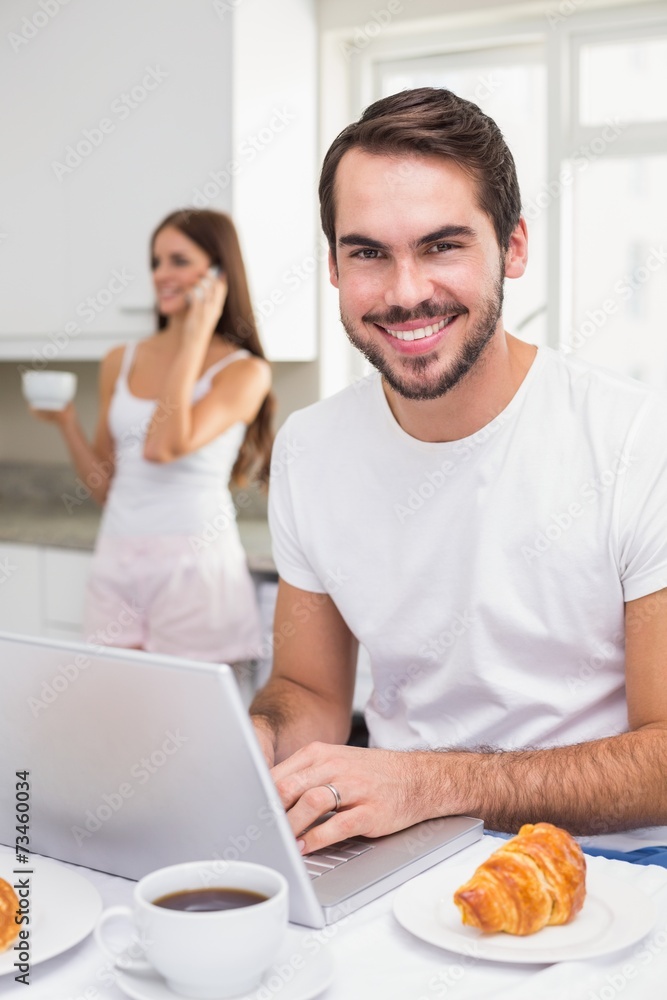 Young man using laptop at breakfast Young man using laptop at breakfast