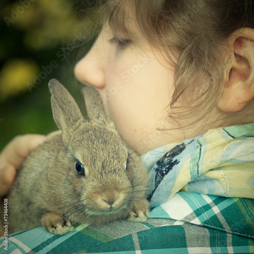 A teenage girl holding a bunny rabbit on her shoulder