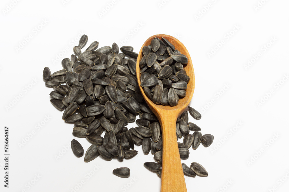 Sunflower seeds on wooden spoon and a handful of sunflower seeds
