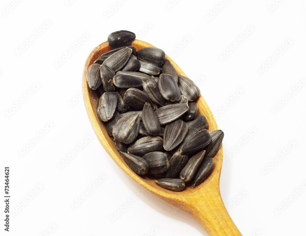 Sunflower seeds on wooden spoon on white background