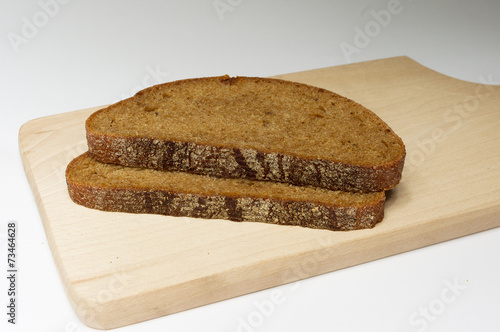 Obraz na płótnie Two pieces of dark bread on the board w salonie