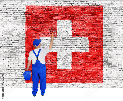 Fotografie House painter covers wall with flag of Switzerland
