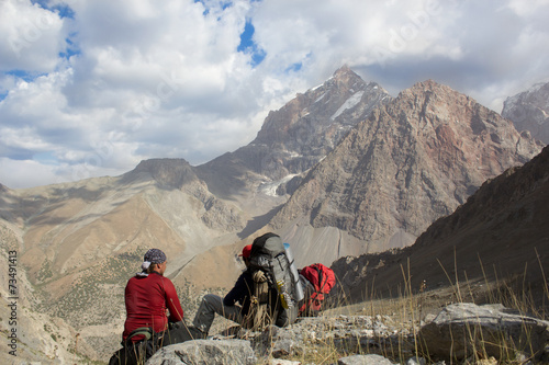 two hikers with backpackers sitting on rest