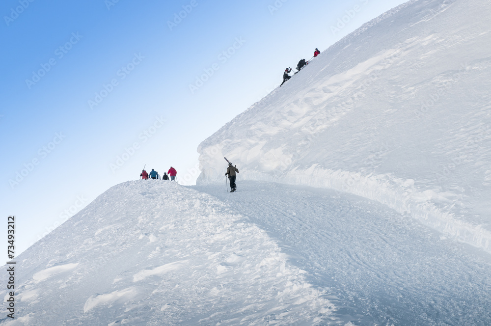 Group of skiers walks up the hill
