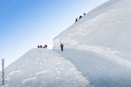 Group of skiers walks up the hill