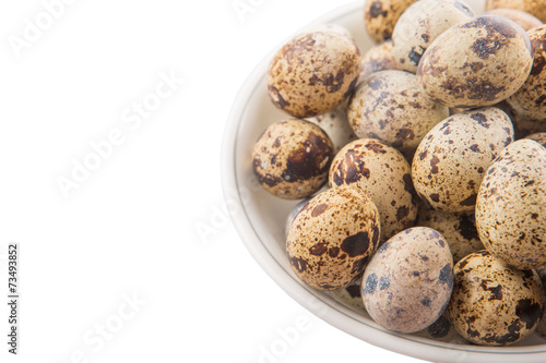 Quail eggs in a white bowl over white background 