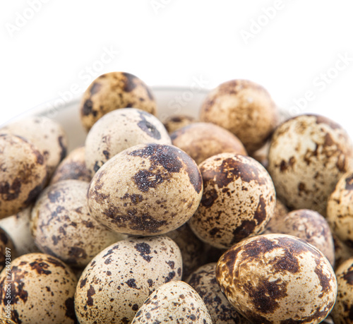 Quail eggs in a white bowl over white background 