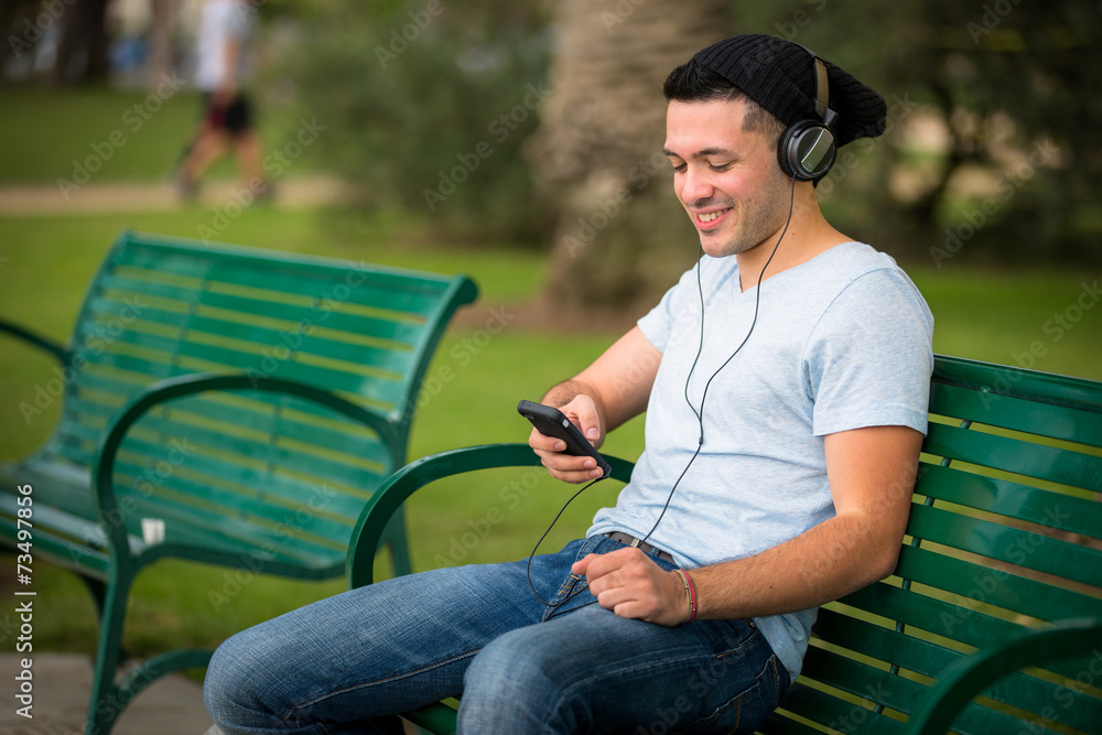 Obraz premium Young male using his cell phone in the park