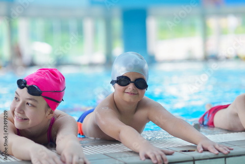 group of happy kids children at swimming pool class learning to 