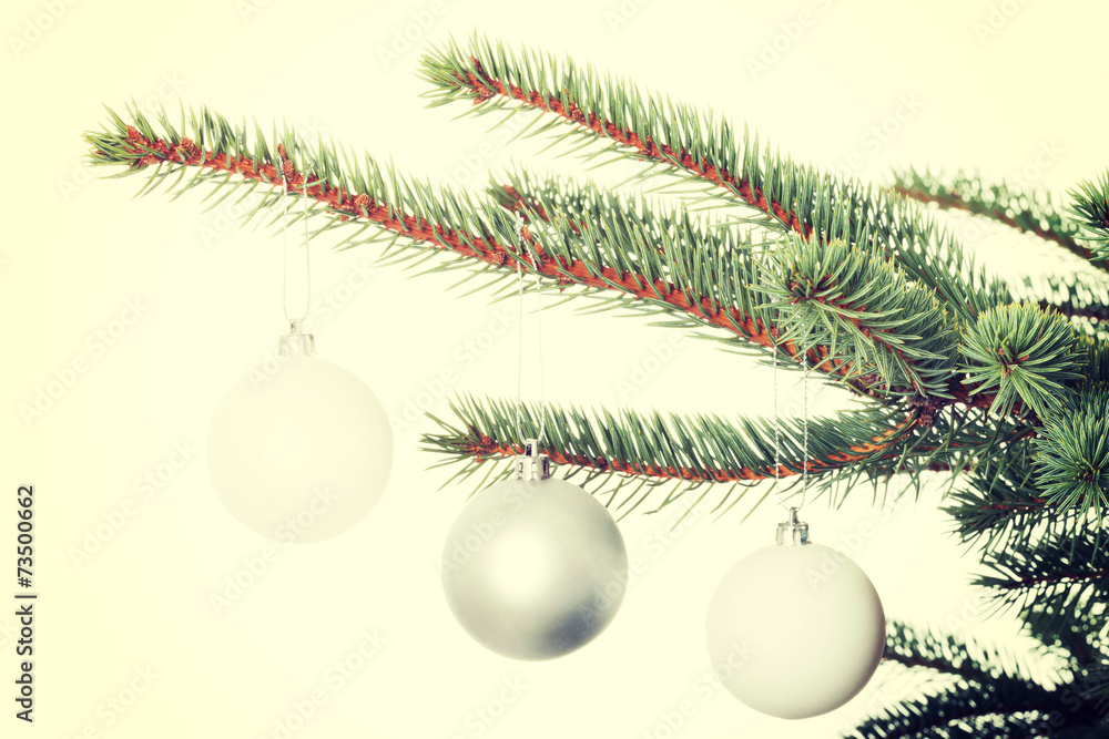 Three christmas balls hanging on a twig.