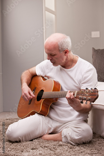 mature man playing guitar at home
