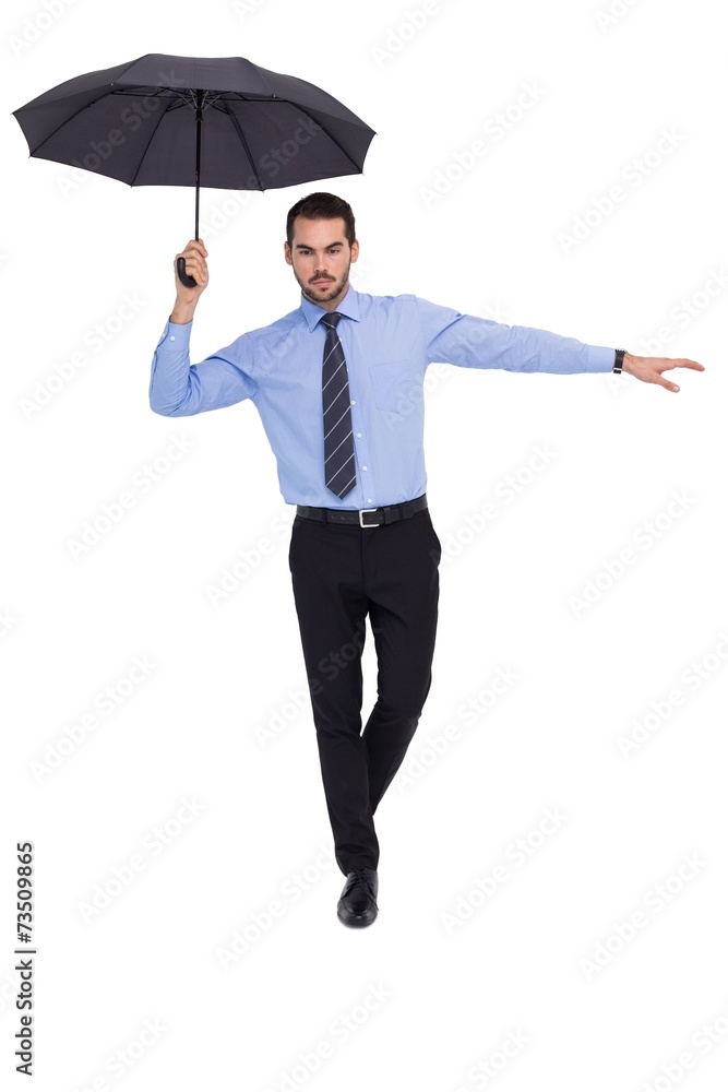 Concentrated businessman with umbrella balancing Concentrated businessman with umbrella balancing