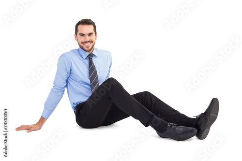 Happy businessman sitting on floor