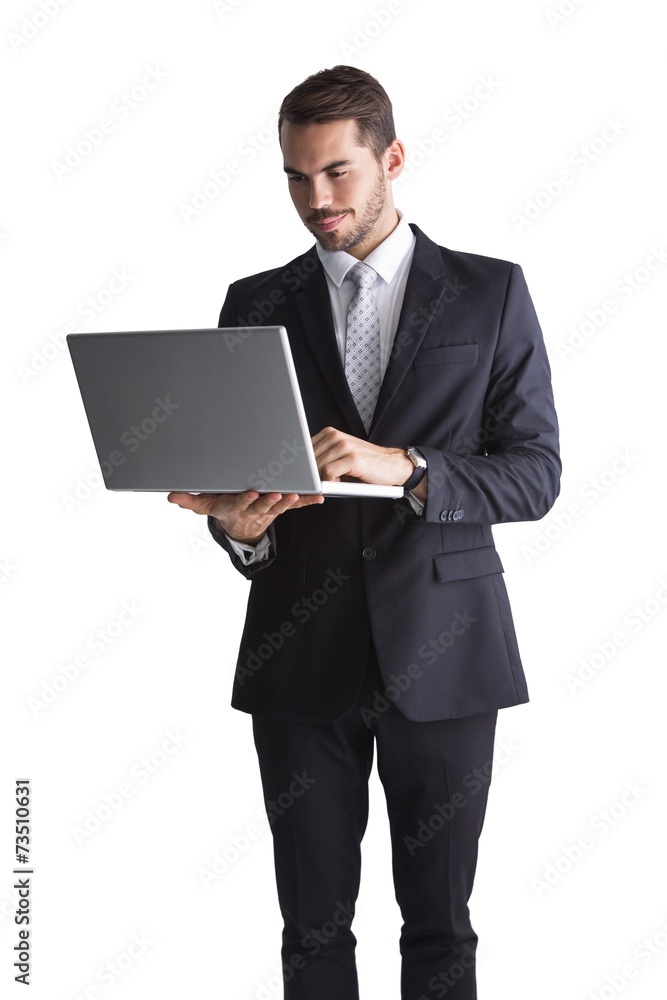 Smiling businessman standing using laptop
