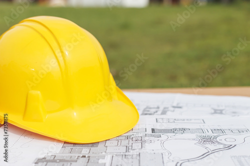 Close up Yellow safety helmet and floor plan drawings on the tab