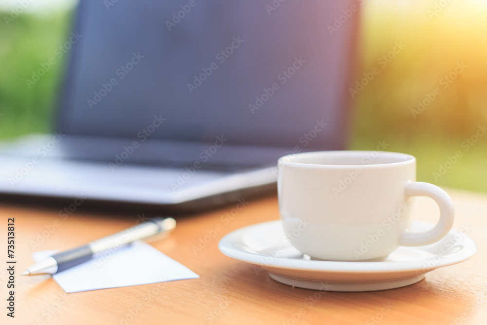 Close up coffee cup and laptop on the table in the morning Close up coffee cup and laptop on the table in the morning