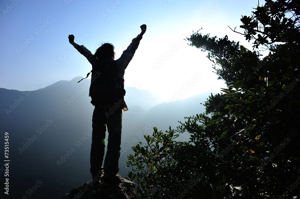 cheering woman hiker open arms at mountain peak 