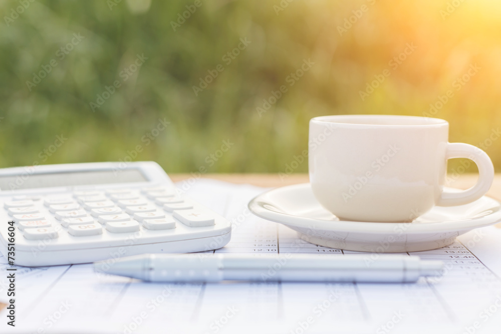 A cup of coffee on the table and calculator with number in paper A cup of coffee on the table and calculator with number in paper