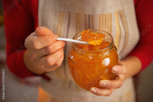 Closeup on young housewife holding homemade orange jam