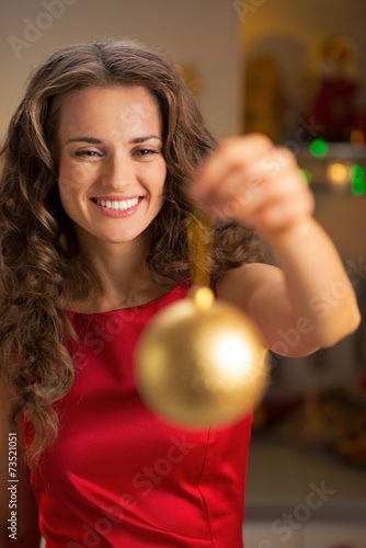 Portrait of happy young housewife showing christmas ball
