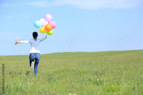 young asian woman on green grassland with colored balloons 