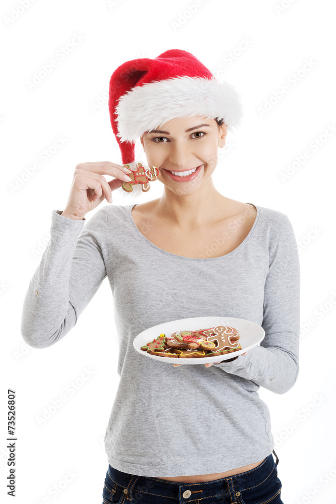 Happy woman in santa hat eating christmas cookies Happy woman in santa hat eating christmas cookies