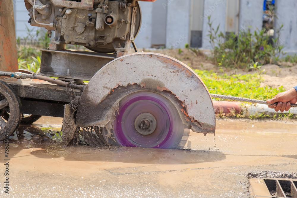 Road workers cutting asphalt road