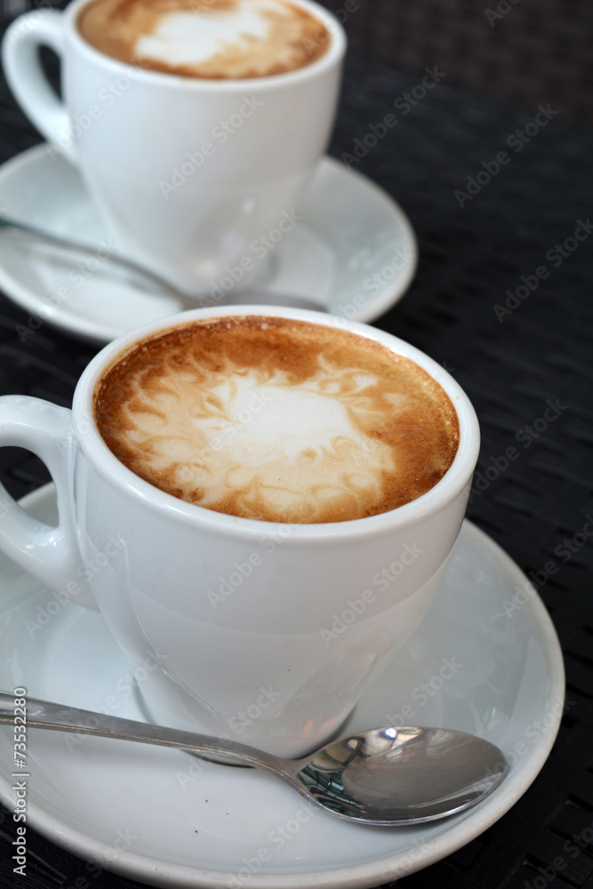 Fototapeta premium Cup of hot cappuccino on the black background