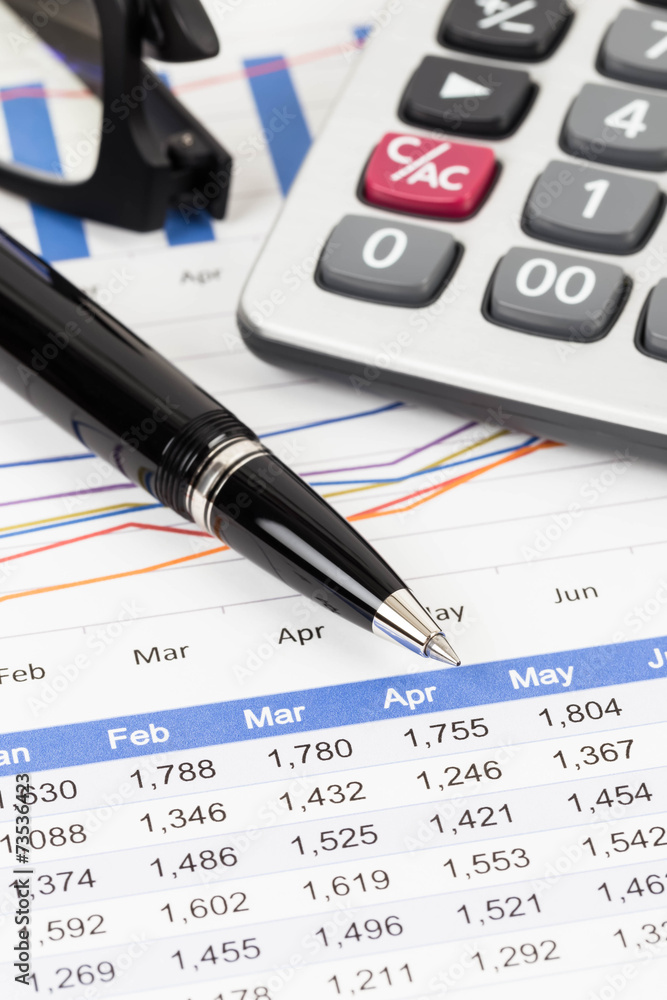 Sales report analysis with pen, calculator, and glasses Sales report analysis with pen, calculator, and glasses