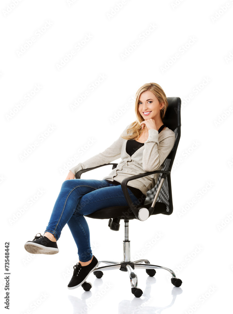 Young woman sitting on armchair touching chin Young woman sitting on armchair touching chin