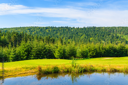 Lake on golf course in Bieszczady Mountains on sunny day, Poland
