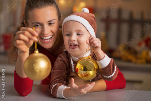 Portrait of smiling mother and baby holding christmas balls